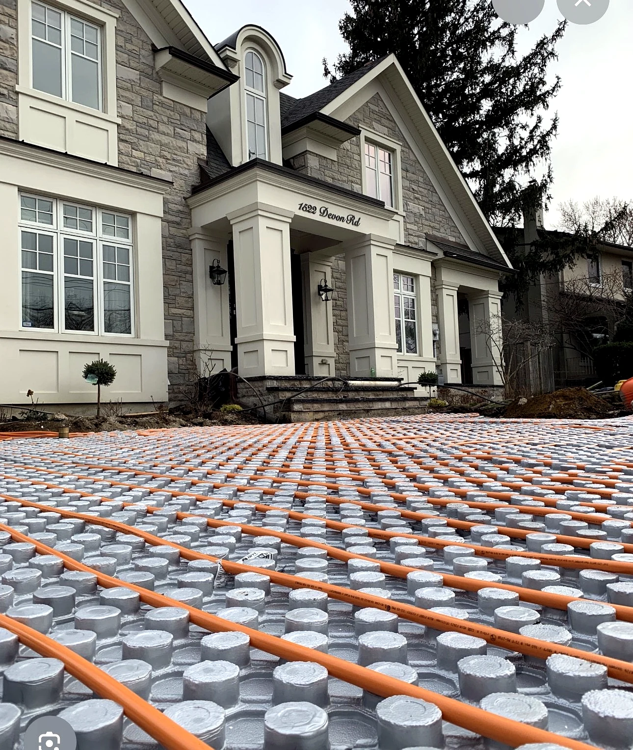 Real Pisces work — full-driveway hydronic snow-melting pipe installation in front of a house