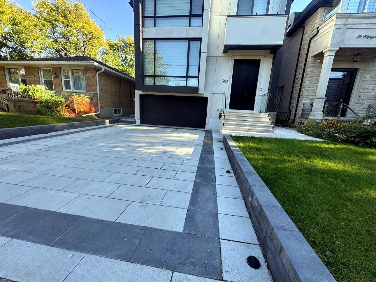 Finished Pisces interlock driveway in Toronto — light-grey pavers with charcoal border accents in front of a modern home