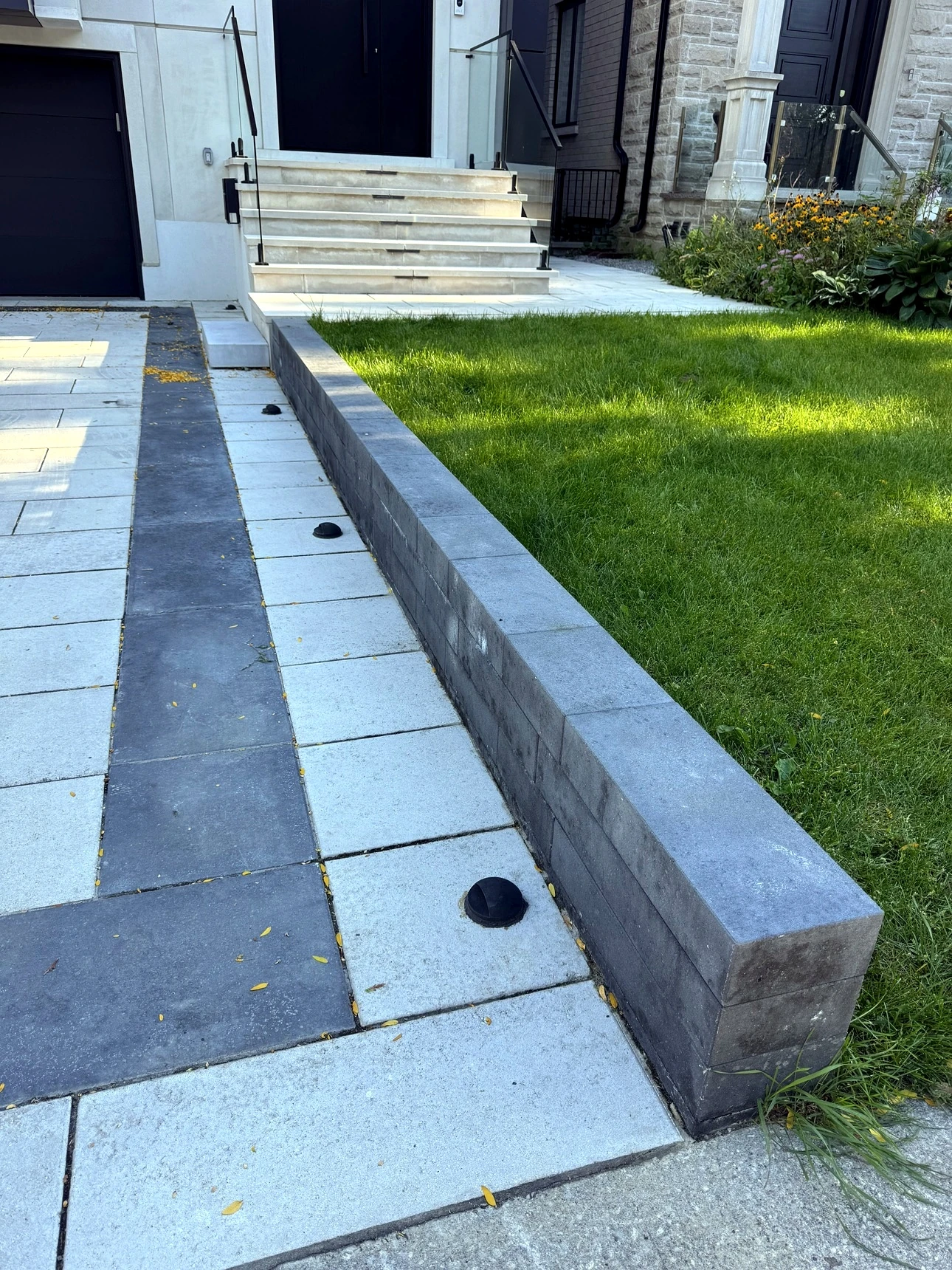 Wide interlock driveway with dark charcoal border frame and retaining wall, Toronto — completed Pisces project